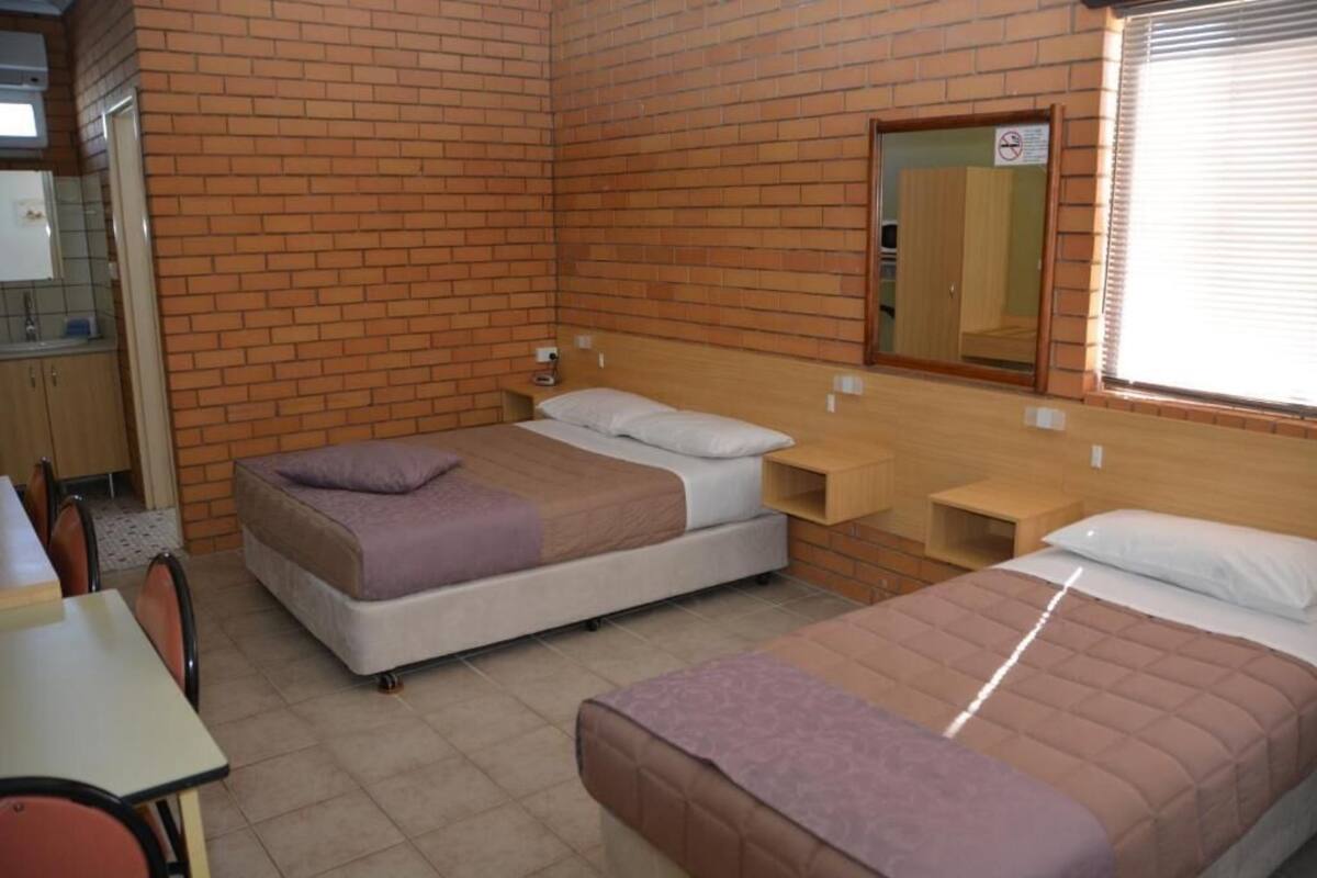 A room with two beds, a small table, and a mirror on the wall.