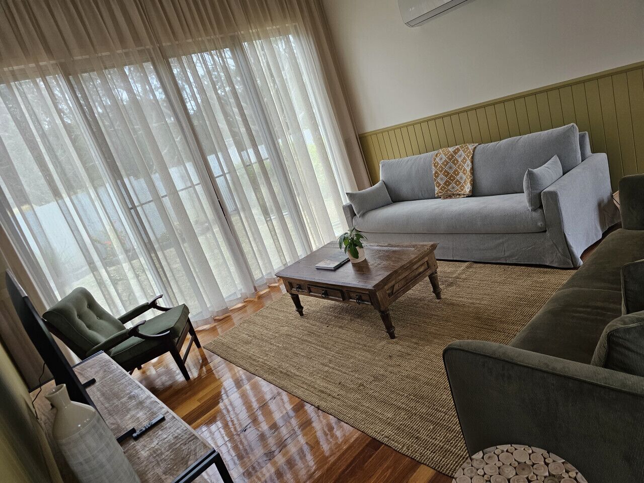Una sala de estar con sofá, sillones, una mesa de centro y una alfombra.