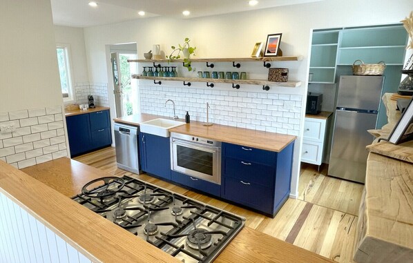 A modern kitchen with a central island, built-in oven, and stainless steel appliances.