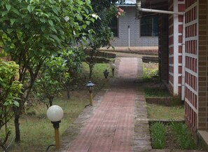 A brick pathway leading to a building with a tiled exterior. - Riverstone Nature Resort (Dapoli)