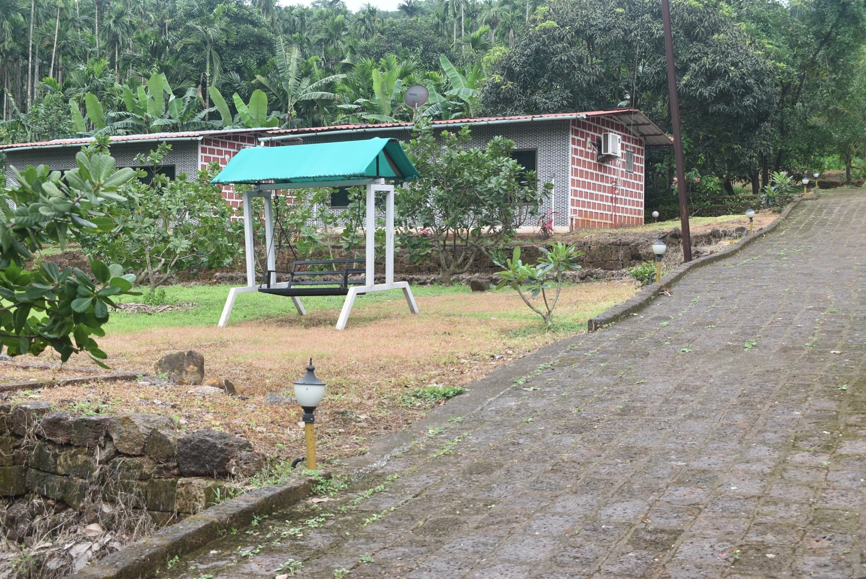 A brick building with a green roof, a swing set, and a paved pathway.