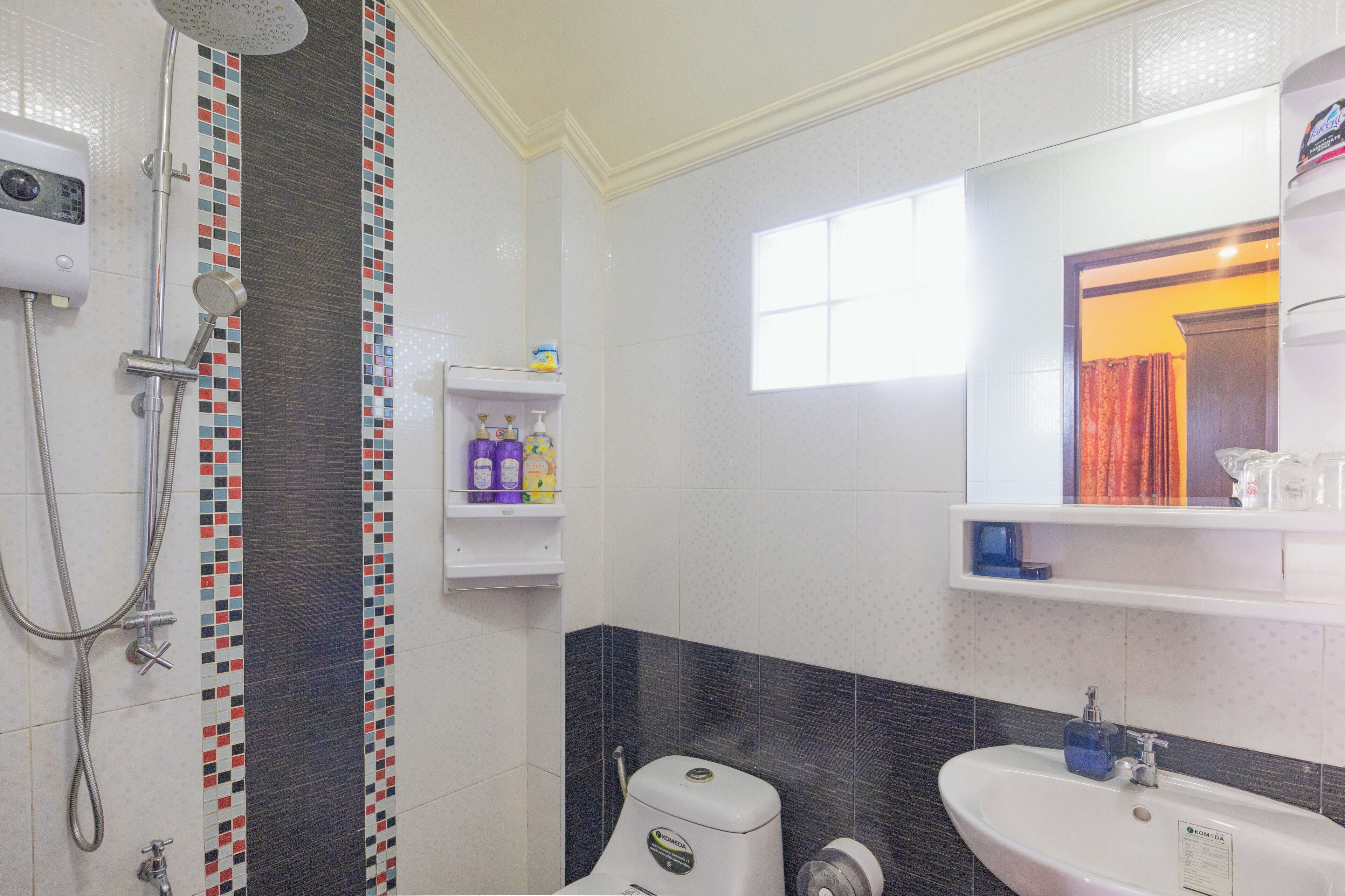 Une salle de bain équipée d’une douche, de toilettes, d’un lavabo et d’un miroir.