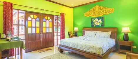 Un dormitorio con una cama grande, cabecera de madera, paredes verdes y un adorno mural.