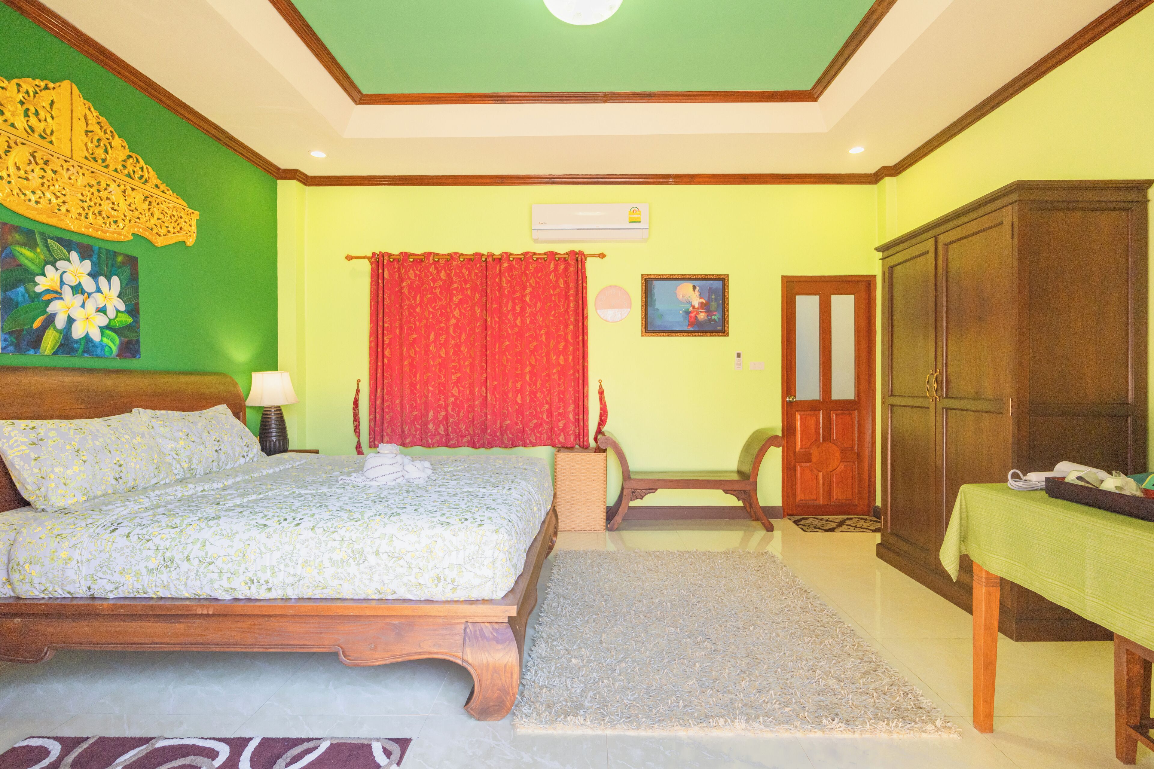 A bedroom with a bed, a wooden wardrobe, a green wall, and a red curtain.