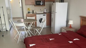 Una habitación de hotel con una cama, una kitchenette pequeña, un comedor y un baño.