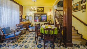 Un coin repas avec une table dressée pour quatre personnes, entourée de chaises. Un escalier avec une rampe en bois mène à l’étage supérieur.