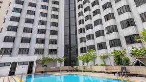 Un immeuble de grande hauteur avec une piscine en premier plan.