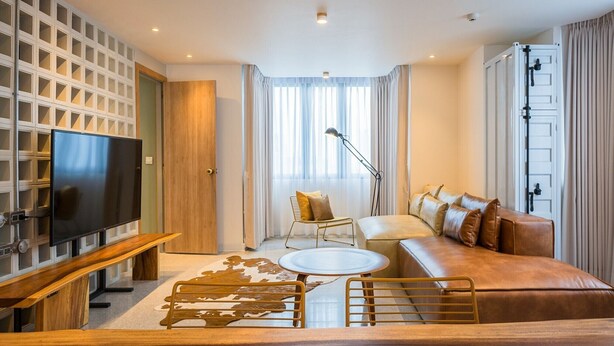 Un salon moderne avec un téléviseur, un canapé, une table basse et un tapis à motifs.