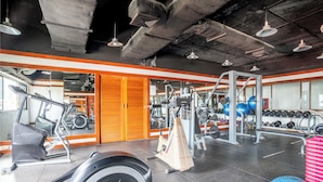 Une salle de sport équipée de matériel d’exercice, de supports pour les poids et d’un mur recouvert de miroirs.