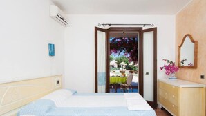 Une chambre avec un lit, une commode et une vue sur un espace repas extérieur.