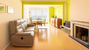 Un salon comprenant un canapé, une table à manger, des chaises, une cheminée et une vue sur la mer.