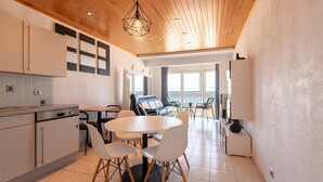 A modern kitchen with white cabinets, a round dining table, and chairs. - Apartment in Mariakerke with Stunning Sea Views (OSTEND)