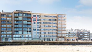 A multi-story hotel with balconies, a beach view, and a sandy foreground. - Apartment in Mariakerke with Stunning Sea Views (OSTEND)