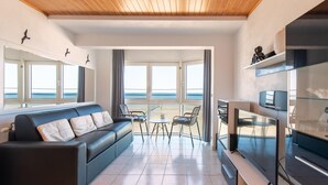 A modern living room with a sofa, chairs, a TV, and large windows overlooking the sea. - Apartment in Mariakerke with Stunning Sea Views (OSTEND)