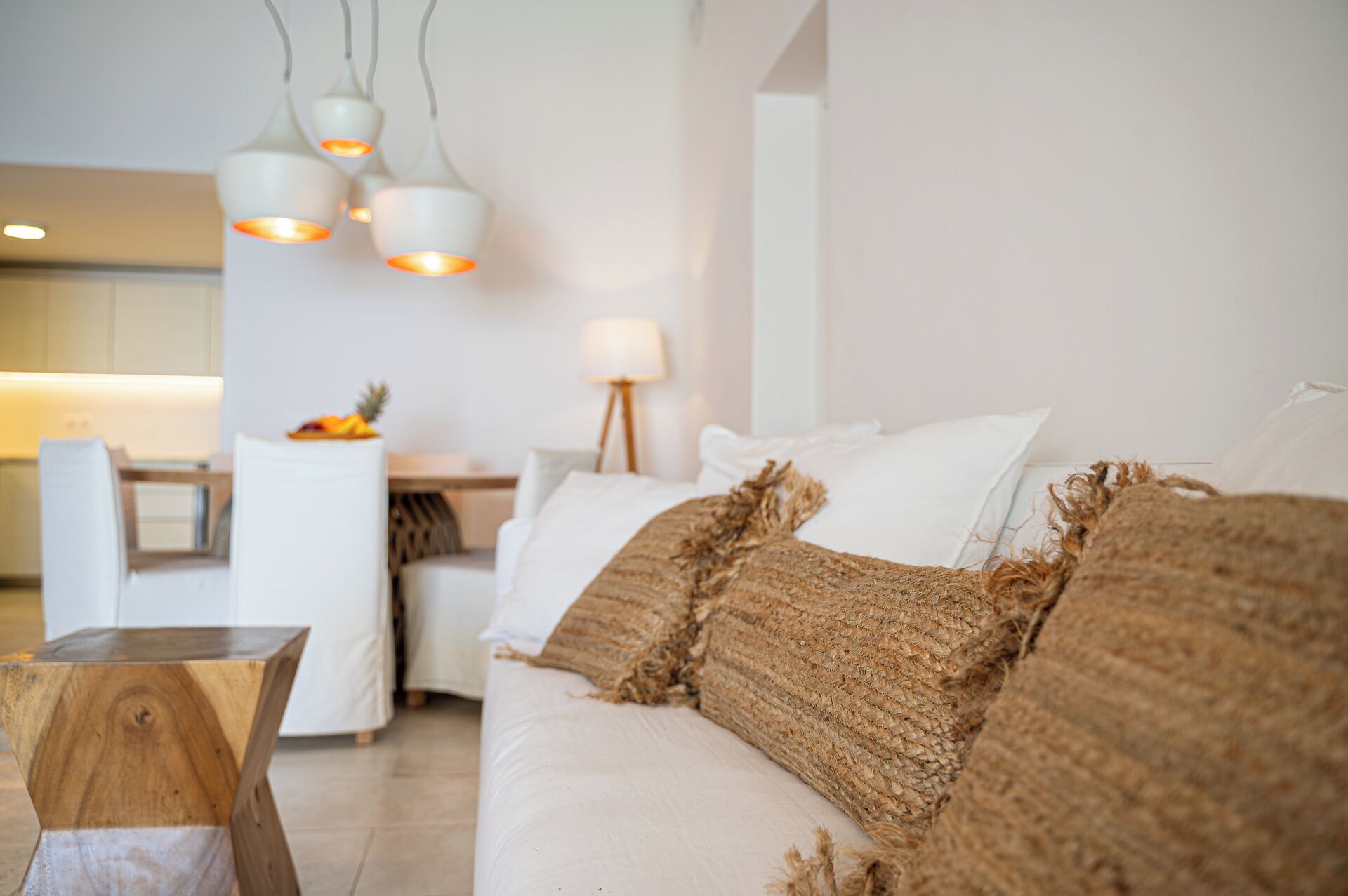Un salon moderne avec un canapé, une table basse en bois et des lampes suspendues.