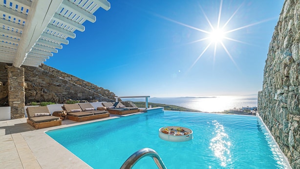 A pool with lounge chairs and a view of the sea.