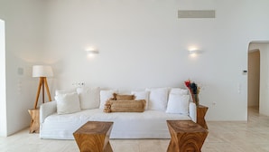 A modern living room with a white sofa, two wooden side tables, and a floor lamp.