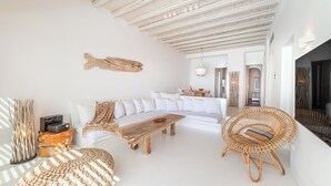 Un ampio soggiorno con un divano bianco, un tavolino in legno e una poltrona in vimini.