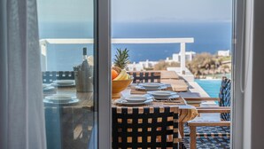 Zona pranzo con vista sull'oceano, una bottiglia e una ciotola di frutta sul tavolo.