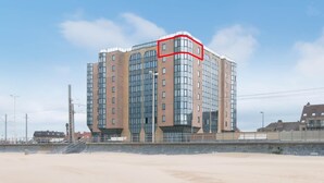 Ett hotell med flera våningar och en modern arkitektonisk design, med stora fönster och en framträdande hörnsektion som markeras av en röd kub.