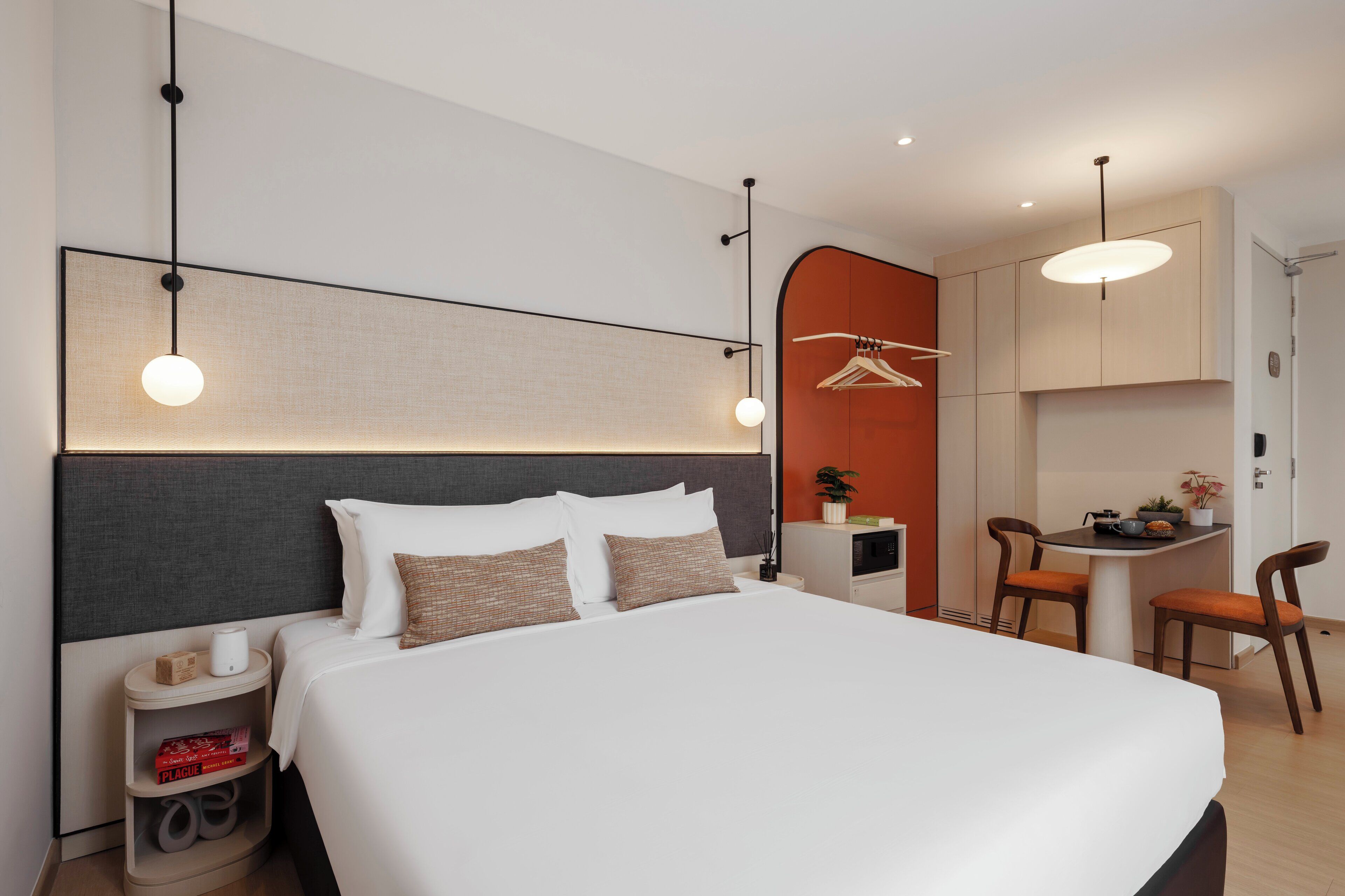 Una habitación de hotel moderna con una cama grande, mesitas de noche, un escritorio y sillas.