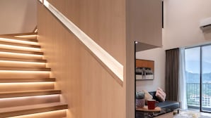 A modern staircase with wooden steps and a handrail, leading to a living area with a sofa and a view of the outdoors. - Citadines Tanjung Tokong Penang (George Town)