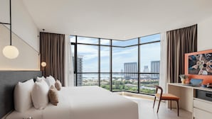 A modern hotel room with a large bed, a desk, and a view of the cityscape. - Citadines Tanjung Tokong Penang (George Town)
