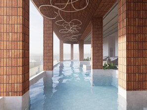 Une piscine intérieure moderne, avec des murs en briques et une vue dégagée sur le paysage urbain.