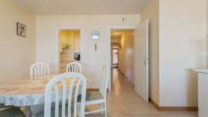 Un comedor con mesa y sillas, una cocina al fondo y un pasillo que conduce a otra habitación.