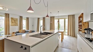 Une cuisine moderne dotée d’un îlot central, de luminaires suspendus et d’un coin repas avec une table et des chaises.