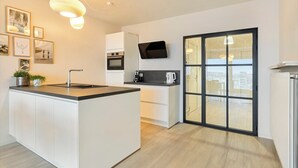 A modern kitchen with a central island, built-in oven, and a large sliding glass door leading to a balcony.