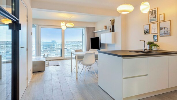 A modern kitchen with a large island, dining area, and a view of the city.