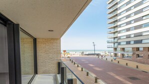 A balcony with a view of a beach and a high-rise building.