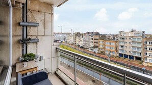 Een balkon met uitzicht op een stadslandschap, met gebouwen en een spoorlijn.