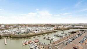 Un puerto deportivo con barcos amarrados, un aparcamiento y un edificio de diseño moderno.