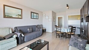 A living room with a sofa, a coffee table, and a dining area with chairs and a table. - Flat in Blankenberge near Belgium Pier (BLANKENBERGE)