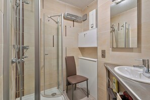 Un bagno con cabina doccia in vetro, un lavandino bianco e uno specchio.