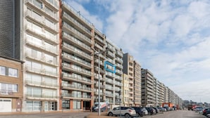 A multi-story residential building with balconies, a parking area, and a clear sky. - Apartment in Blankenberge near Belgium Pier (BLANKENBERGE)