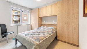 A bedroom with a bed, a chair, a wardrobe, and a window. - Apartment in Blankenberge near Belgium Pier (BLANKENBERGE)
