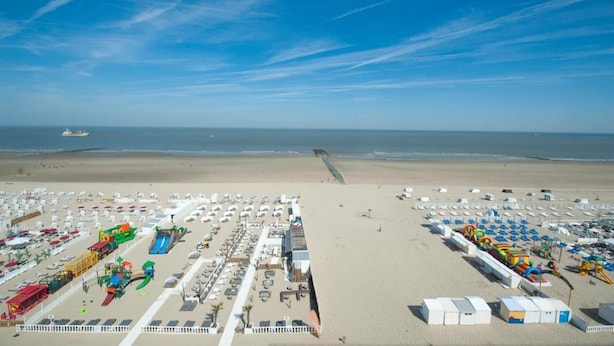 A beach with numerous beach umbrellas and sun loungers, a water slide, and a lifeguard tower. - Apartment in Blankenberge near Belgium Pier (BLANKENBERGE)