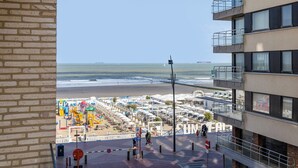 Vista desde un balcón sobre una playa con un paseo marítimo y sombrillas.