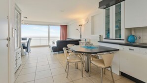 A modern kitchen with a dining area, a view to the sea, and a balcony with a sofa. - Apartment in Blankenberge near Belgium Pier (BLANKENBERGE)