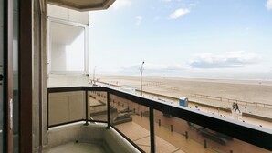 Ein Balkon mit Blick auf einen Strand und einen klaren Himmel.