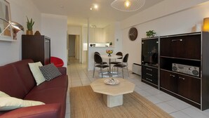 Ein modernes Wohnzimmer mit einem roten Sofa, einem Couchtisch und einem Essbereich mit Stühlen und einem kleinen Tisch.