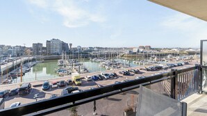 Puerto deportivo con barcos, un estacionamiento y edificios al fondo.