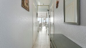 Un pasillo con pared texturizada, un cuadro enmarcado y un espejo.