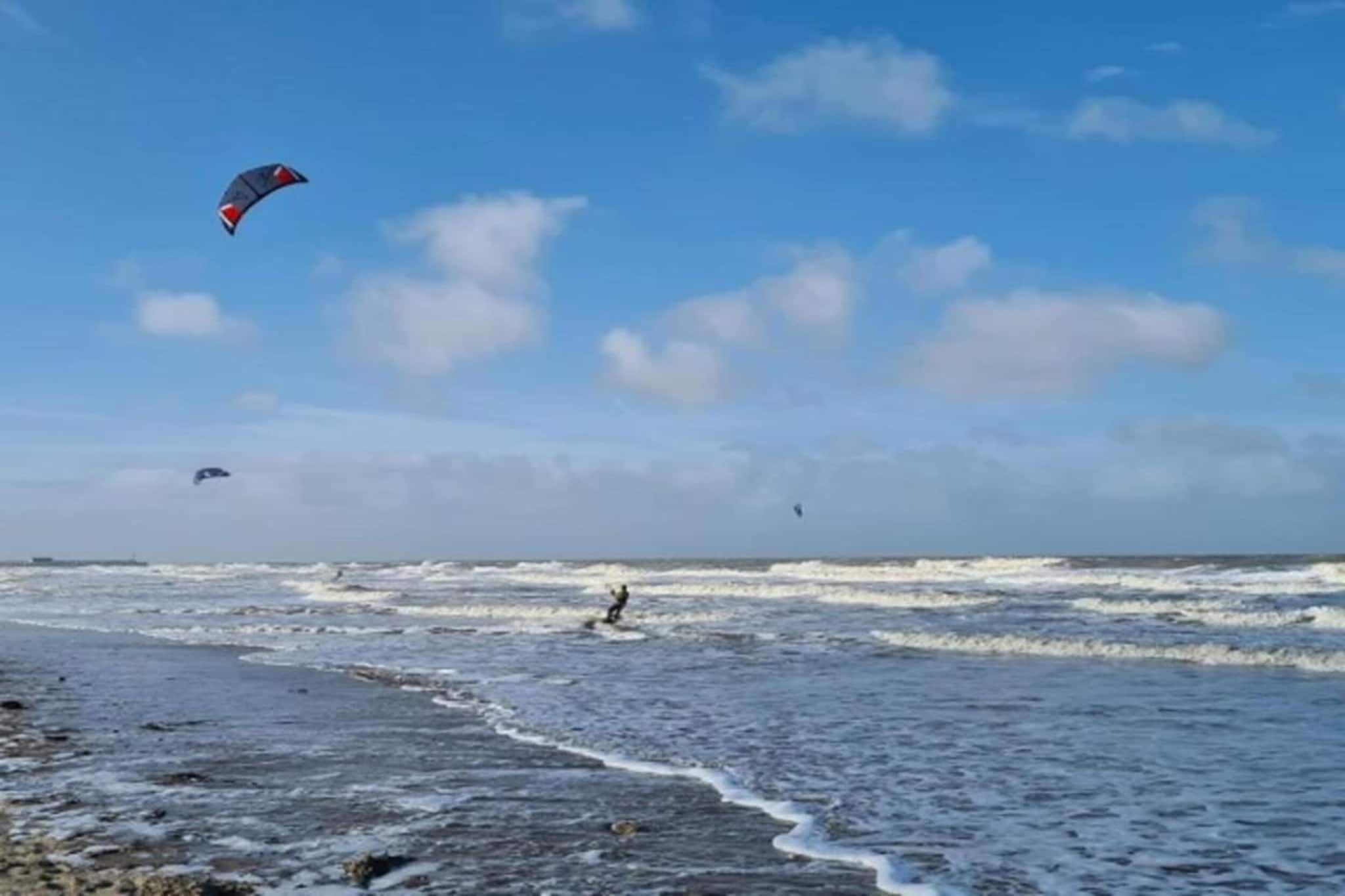 A beach with waves and a person surfing.