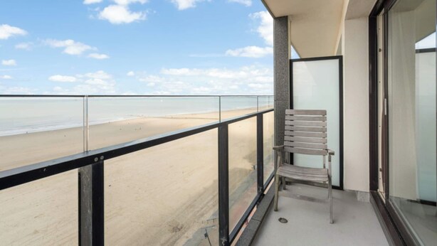 A balcony with a view of the beach, a metal railing, and a wooden bench. - Apartment in Blankenberge with Sea Views (BLANKENBERGE)