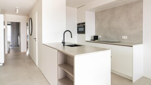 A modern kitchen with a central island, built-in oven, and a large grey backsplash.