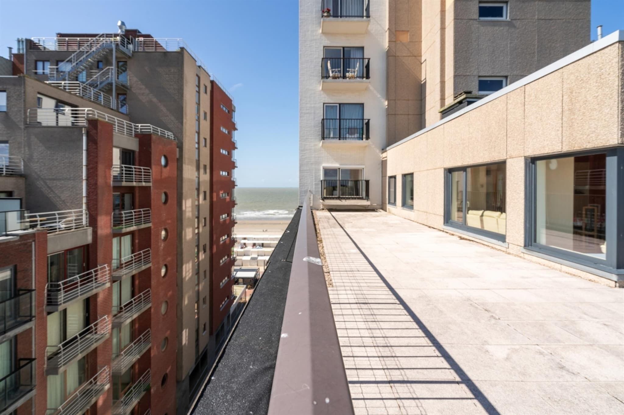 Un edificio moderno con varios pisos, balcones y grandes ventanales.